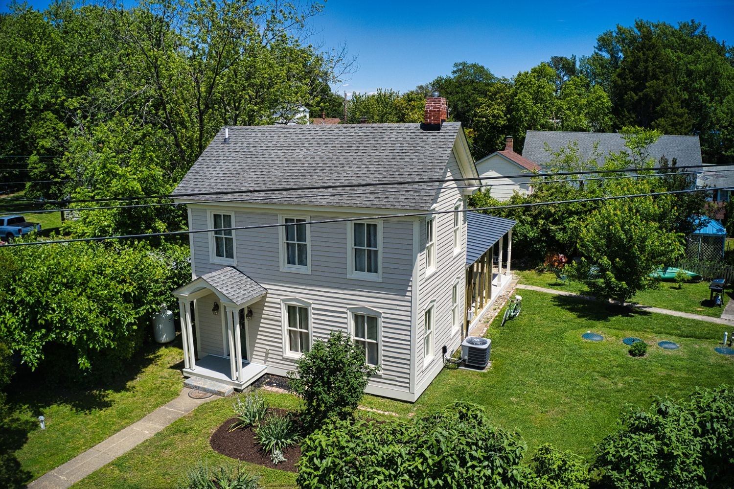 Privacy is achieved through dense landscaping while original wood siding restoration highlights period authenticity.