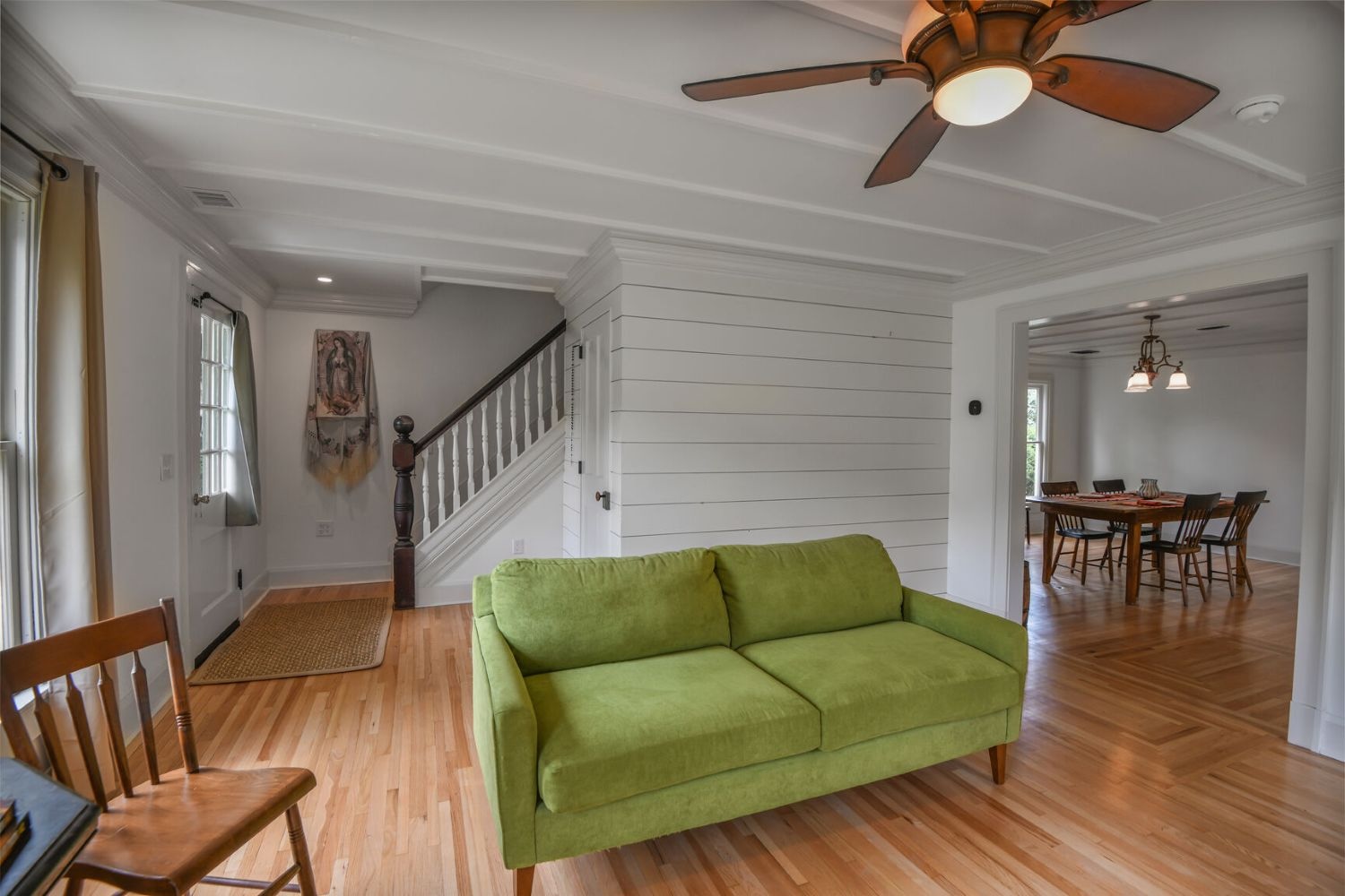 Shiplap walls, ceiling molding, and timeless wood floors create texture and elegance in the compact living space.